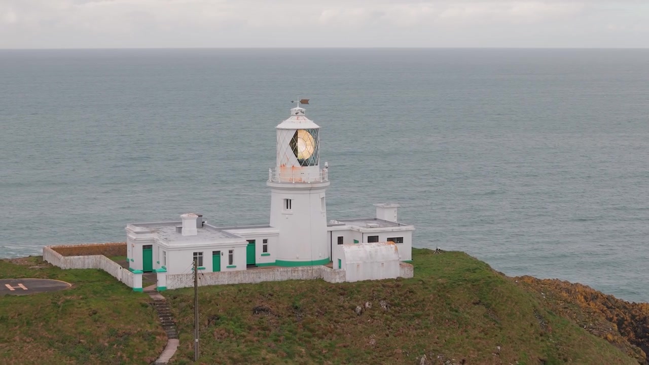 Vista aerea del faro di Strumble Head verso la torre faro sulla costa frastagliata del Pembrokeshire