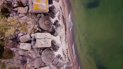 vista aérea de pájaros del edificio de fortificación costero abandonado en los fuertes del norte de karosta en la playa del mar báltico en liepaja en un día nublado de primavera, mar en calma, amplio tiro de drones avanzando