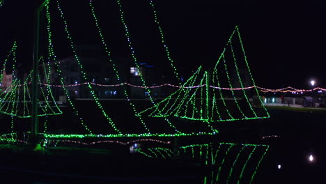 aerial pullback from galway hooker boats with string lights at night