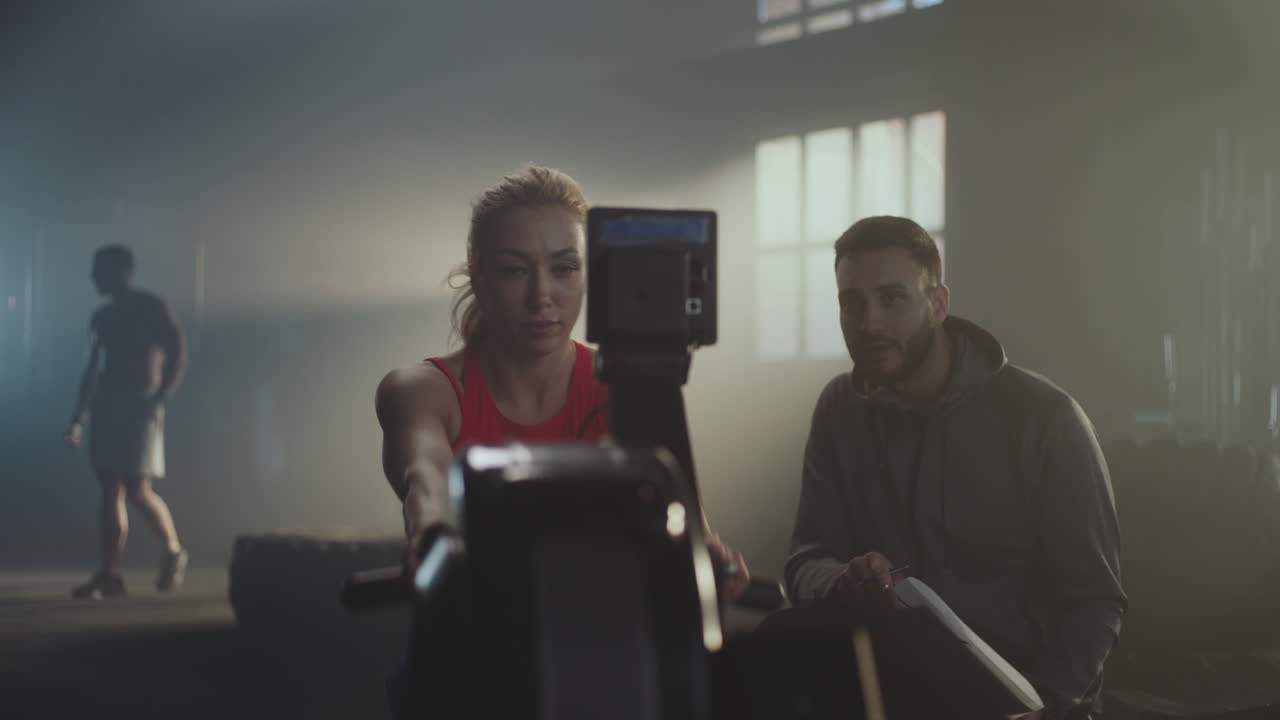 Woman training on rowing machine with personal trainer