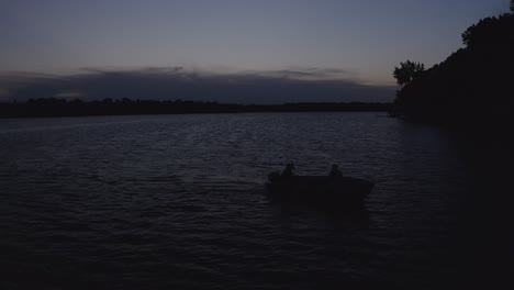 aerial shot of a silhouetted fishing boat on lake during twilight