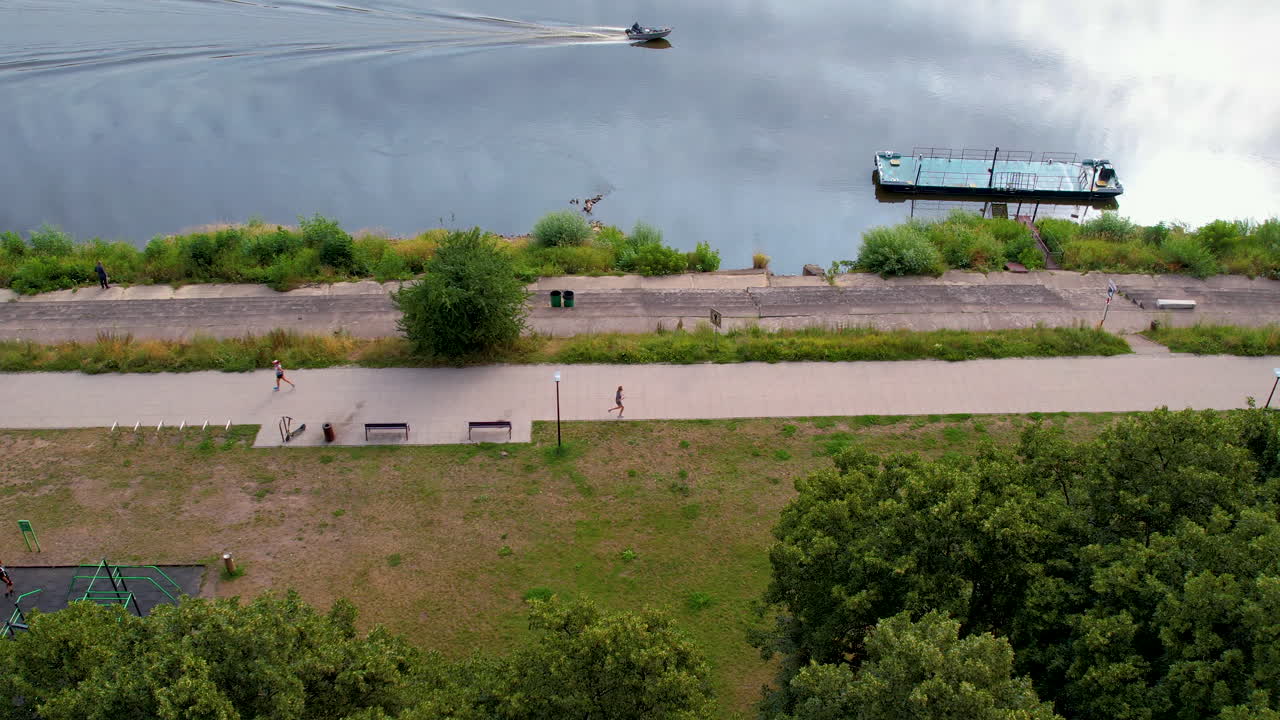 дрон следит за бегуном по пути к спокойной реке.