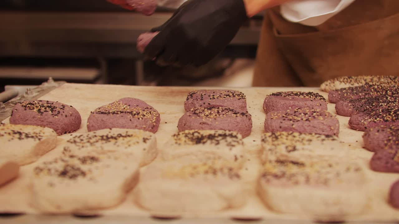 Nahaufnahme eines Bäckermeisters, der verschiedene frische handwerkliche Brötchen und Baguettes nach traditionellem Rezept zubereitet. Ein junger Mann knetet Teig. Handwerklich hergestelltes Brot wird von erfahrenen Bäckern mit natürlichen und hochwertigen Zutaten hergestellt. Lebensmittel mit Gesundheits- und Geschmacksvorteilen. Bäckerei und Markt.