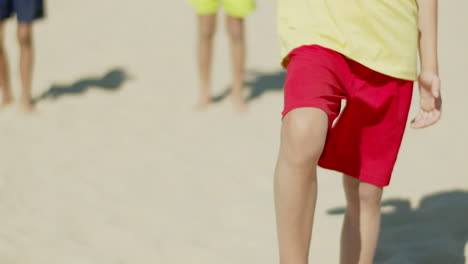 vertical motion of boy standing on shore with foot on ball