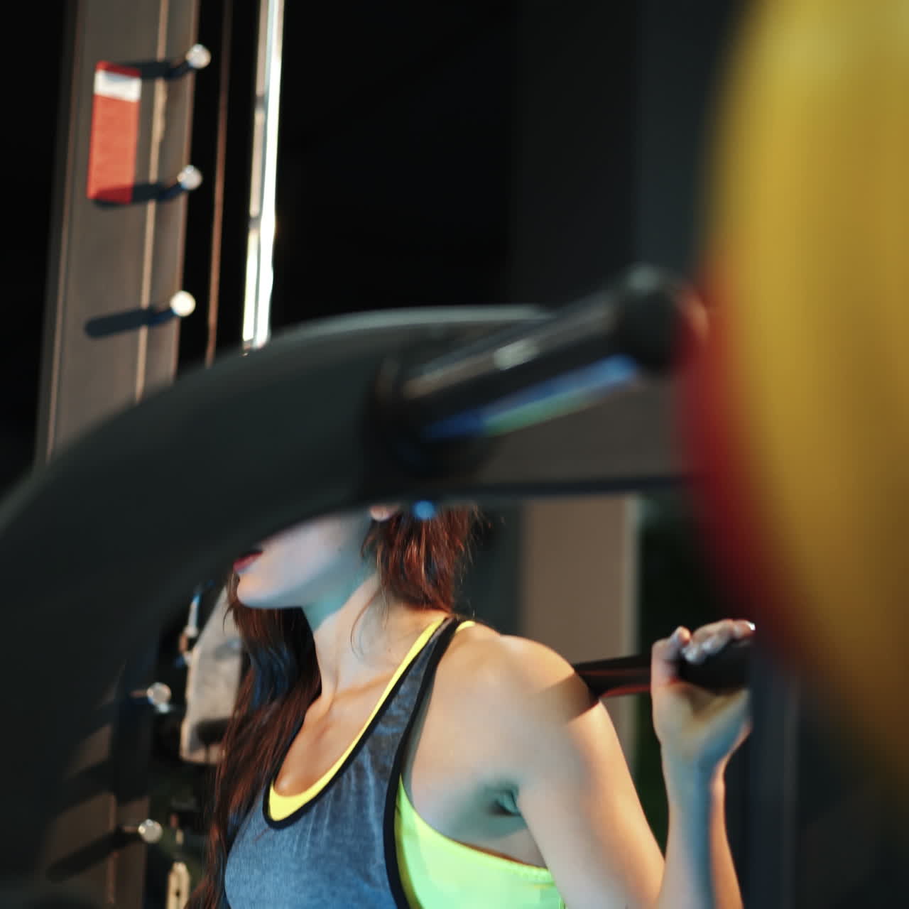 Fitness woman doing sit-ups with a barbell in the gym. Smith's machine in the gym. The ideal female figure. Fitness is the concept of a healthy lifestyle. Square video