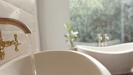 close up of washbasin with running water in bathroom, slow motion