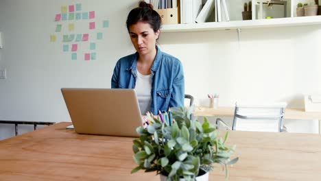 ejecutiva sentada en un escritorio y usando una computadora portátil
