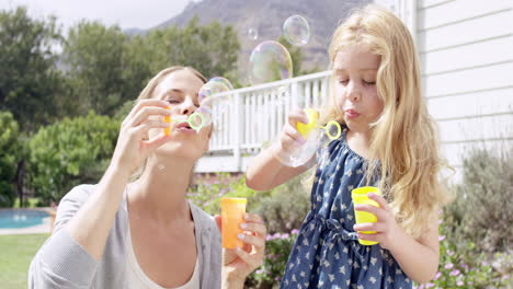 mother and daughter blowing bubbles in the yard happy family home