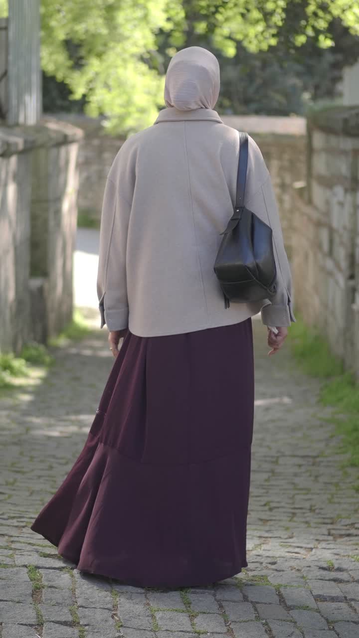 Muslim Woman in Hijab Walking Down a Cobblestone Alley