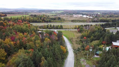 Experience-stunning-aerial-views-as-a-drone-glides-over-a-scenic-country-road,-tracing-the-path-of-powerlines-and-a-bustling-highway-below