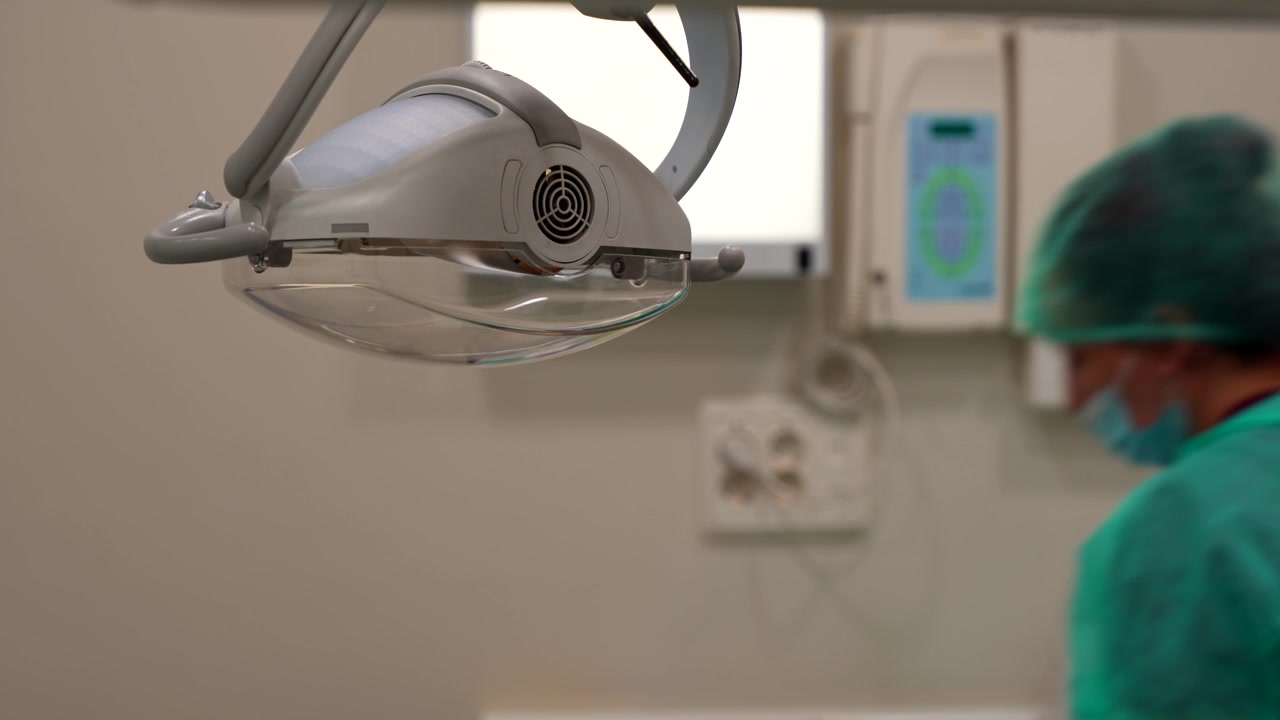 Close-up of dentist chair lamp in focus and blurred dentists in background