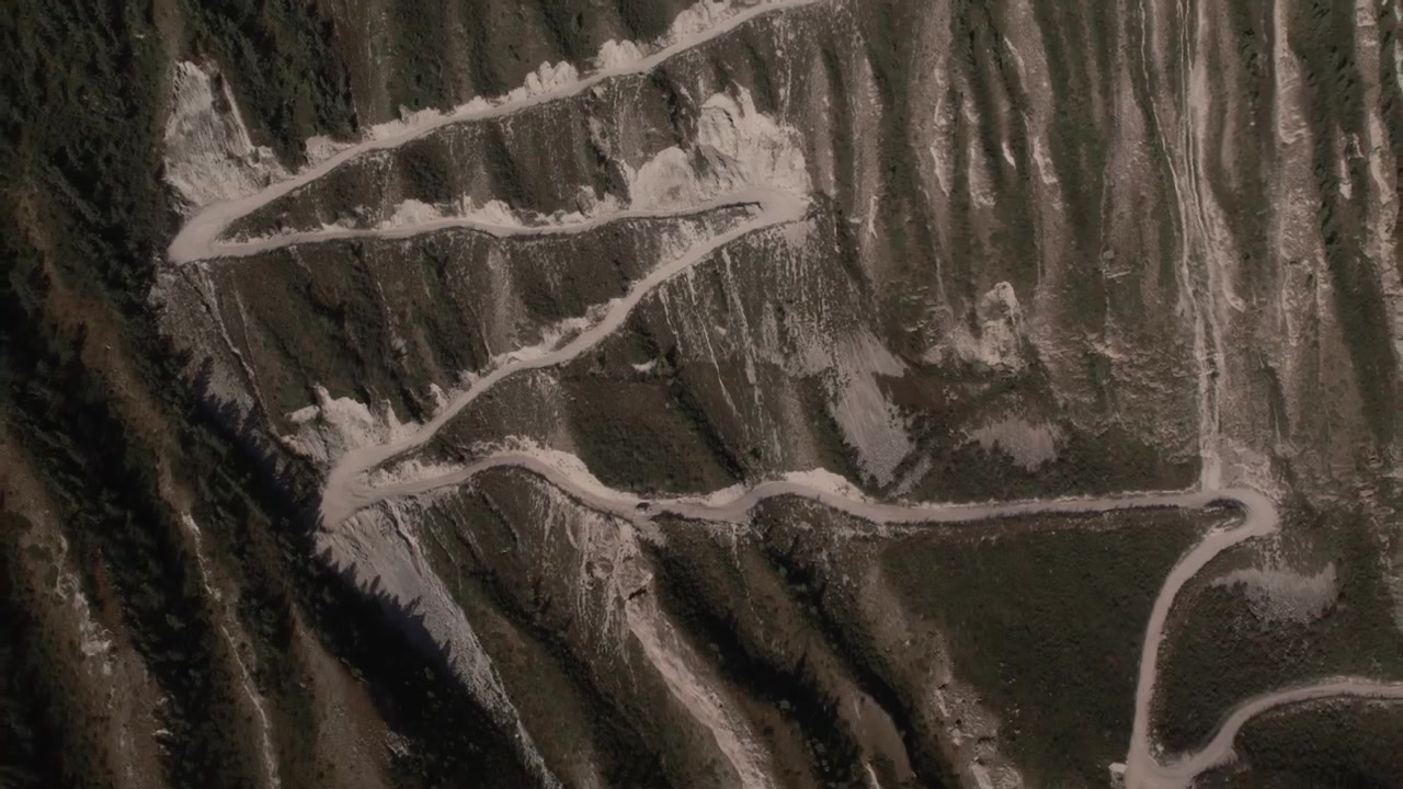 Riprese con drone della ripida strada serpeggiante che scende dal Passo Katu-Yaryk sopra un canyon aspro e una foresta di taiga sui Monti Altai, Russia, giornata di sole