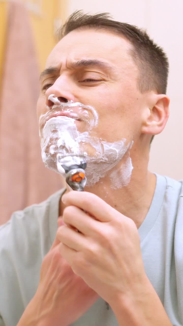 Uomo che si rade la barba allo specchio del bagno