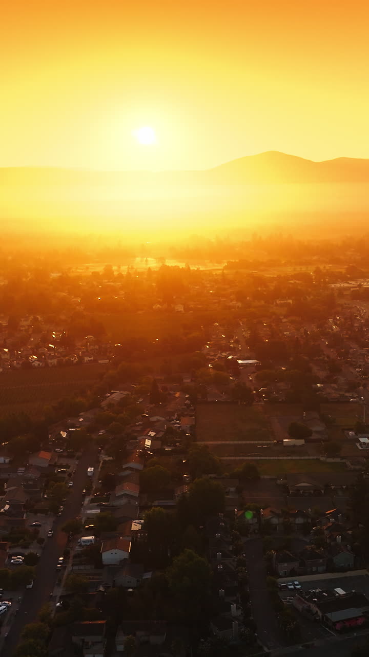 Sunlit panorama of Napa city, California, USA. Drone footage over the valley at backdrop of orange skies and bright sun. Vertical video