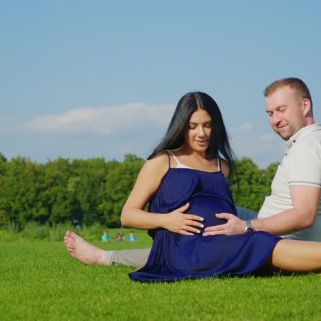 husband with a pregnant wife is lying on the green grass 1