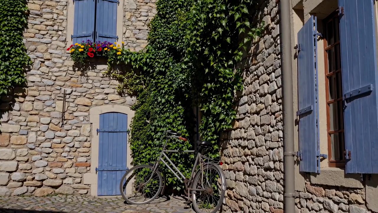 Bicicletta d'epoca appoggiata a un muro di pietra rustico in un borgo europeo