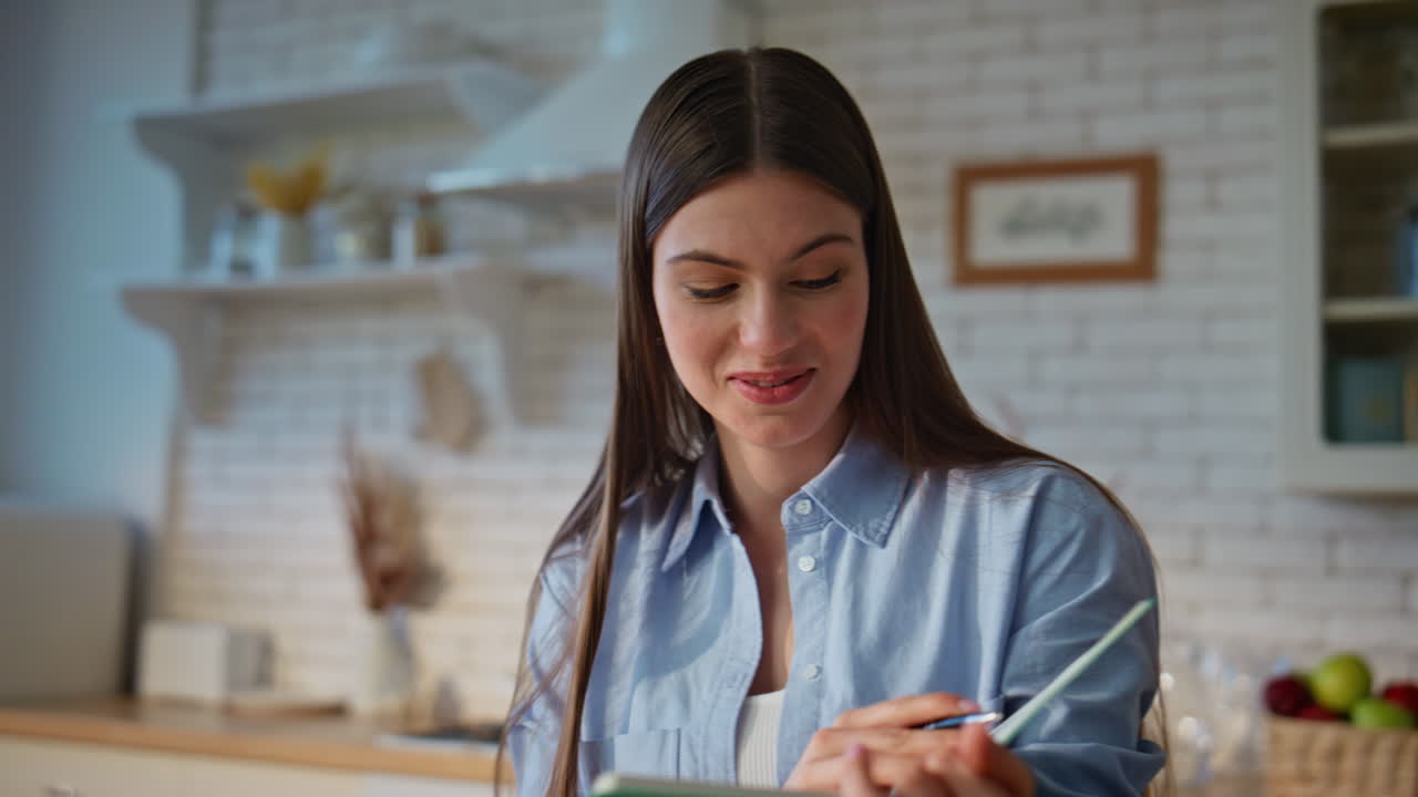 Online tutor reading notes to laptop webcam at kitchen closeup. Remote teacher