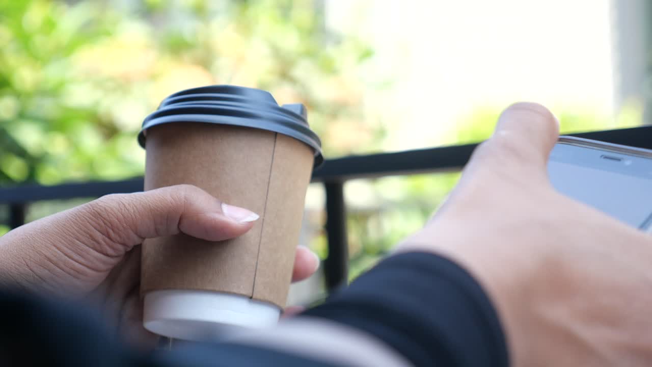 Person holding coffee cup and mobile phone