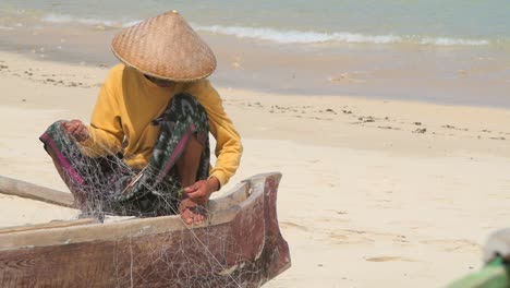 indonesian fisherman untangling nets on a canoe