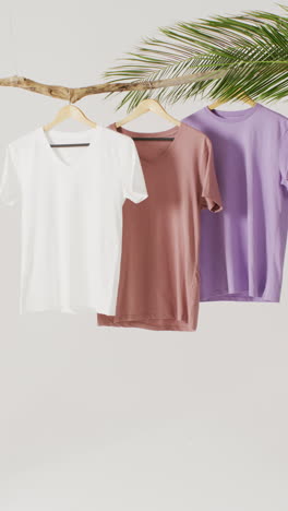 vertical video of close up of white, brown and purple t shirts hanging with copy space