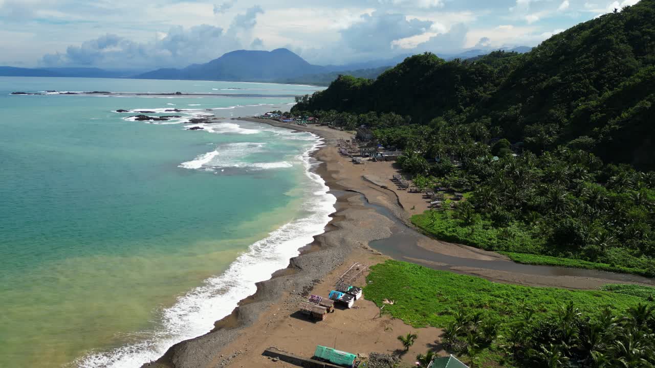 Forward aerial of Dingalan, Aurora, gliding above lush greenery and a sandy road that winds toward the iconic Matawe Rock Formations along the turquoise coastal waters