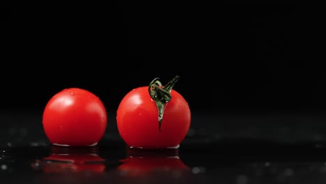 two fresh cherry tomatoes on black background