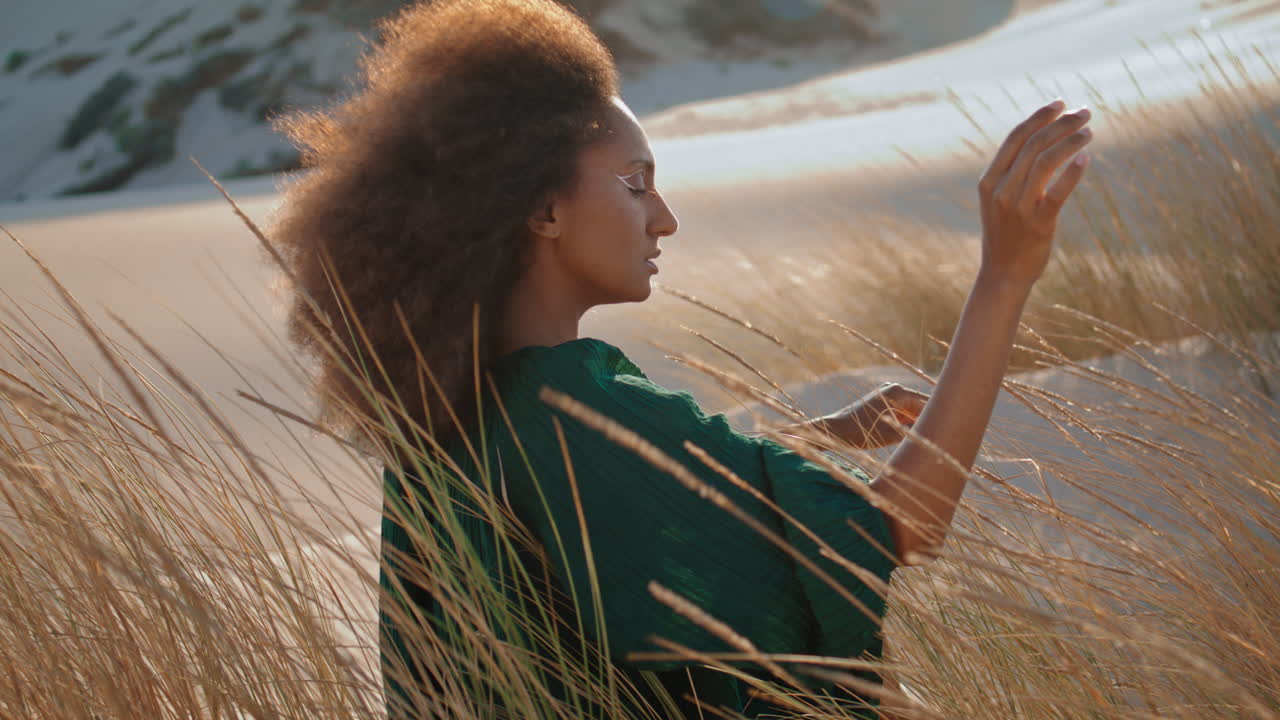 Woman enjoy desert nature sitting on sand with dry grass swaying wind close up.