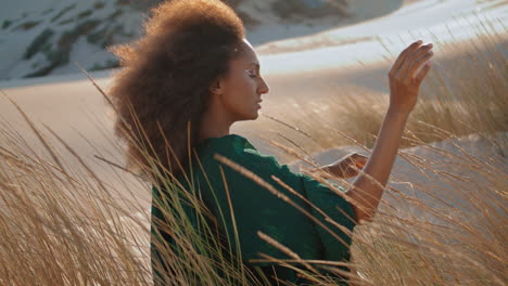 la mujer disfruta de la naturaleza del desierto sentada en la arena con la hierba seca balanceándose el viento de cerca.