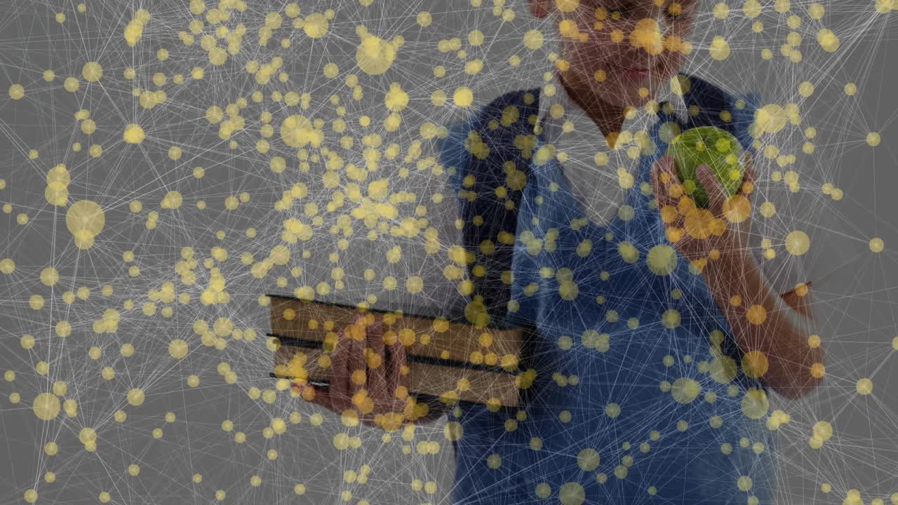 School-aged boy holding books and inspecting green apple in education session before offering snack