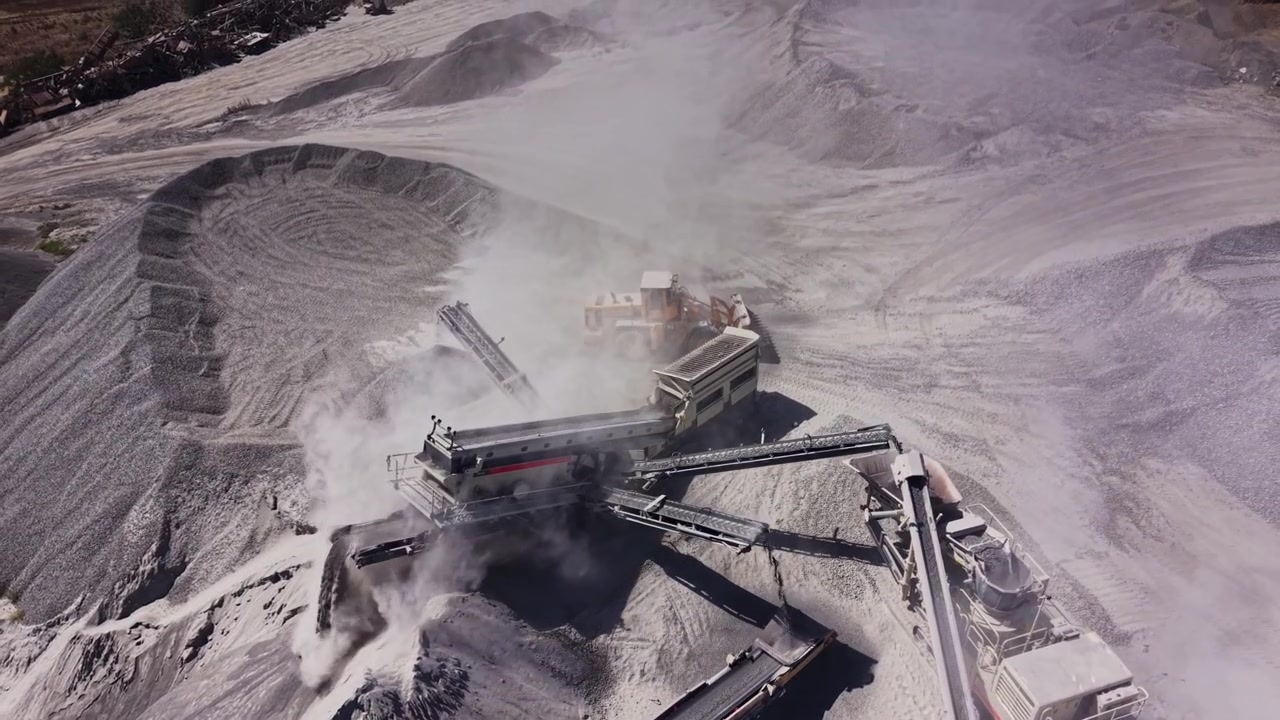 Machine working at a gravel site during the day in a dusty environment