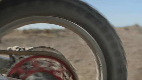 SLOW-MOTION:-A-Honda-dirt-bike-rider-shifts-into-first-gear-and-takes-off-quickly,-kicking-up-dirt-and-sand,-as-he-races-into-the-desert