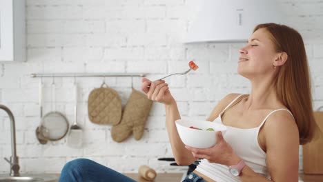 a vegetarian girl sits in the kitchen and eats salad from a plate. healthy diet for weight loss