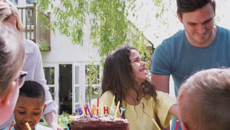 parents with daughter celebrating birthday with friends having party in garden at home