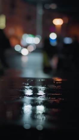 blurred view of cars passing with headlights on a wet city street at night, creating vibrant light reflections