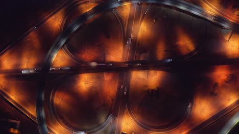 road intersection, bridges, highways and car traffic in blurred speed motion, aerial top view at night