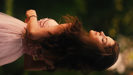 Horizontal-shot-of-a-gorgeous-young-brunette-woman-playing-with-her-long-hair,-wearing-exquisite-pink-gown-with-blurred-background