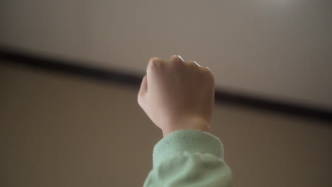 close up of female hand in fist opening with forearm upward against blurry background.