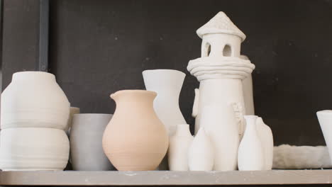 close up of various ceramic pieces on a wooden shelf in the pottery shop