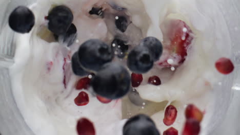 berries dropped mixing milk in super slow motion close up. vitamin cocktail.