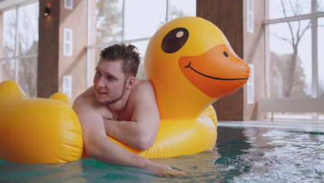 happy man in water park lying on inflatable duck in swimming pool joyful and relaxed male visitor