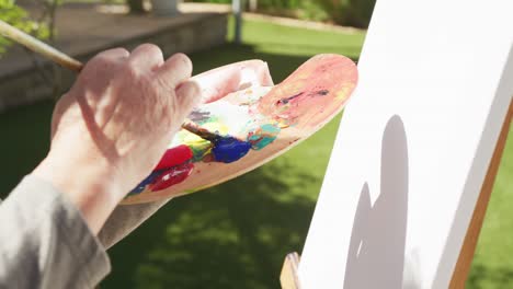 primer plano de una mujer mayor asiática pintando en el jardín en un día soleado