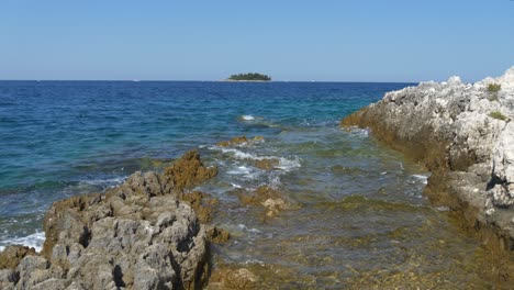 calm adriatic sea in croatia with island in the background and rocks in the foreground