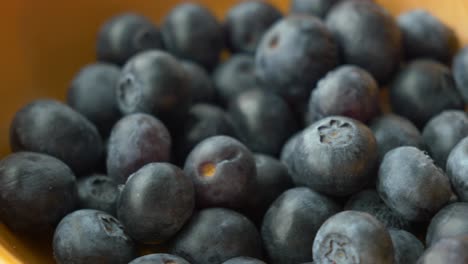 Close-up-of-fresh-blue-berry-fruit-in-a-orange--bowl-on-table-,