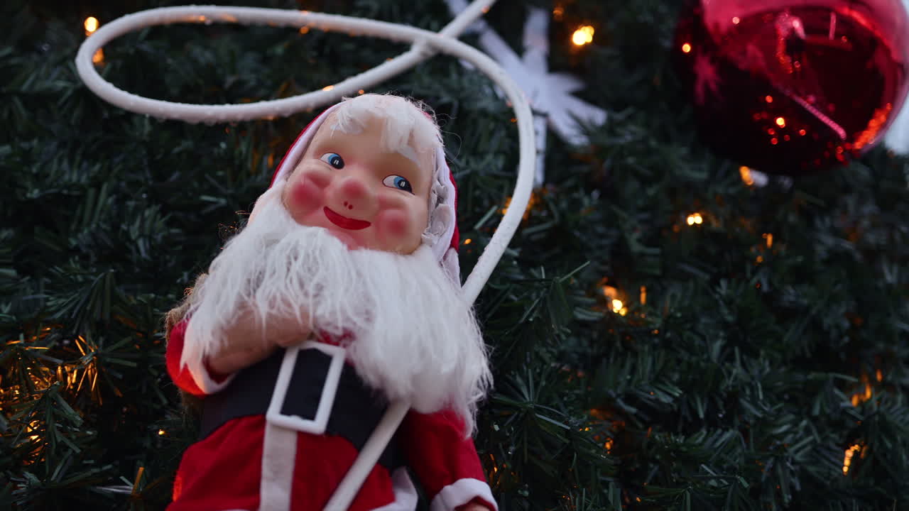 Decorazione festiva di Babbo Natale esposta all'aperto, incorniciata da rami di albero di Natale e luci calde delle feste