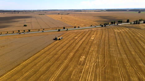 unloading grain onto a trailer in the middle of the field, beautiful field scenery close to the roadway, combine and tractor on the field