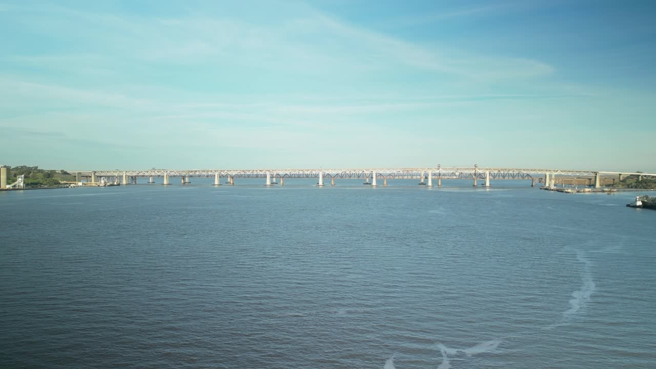 Drone slow approach to bridges across Carquinez Strait, shoreline and wetlands in Martinez, California, with rolling hills