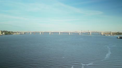 drone slow approach to bridges across carquinez strait, shoreline and wetlands in martinez, california, with rolling hills
