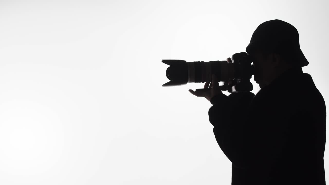 Silhouette of a photographer with a long lens taking pictures - Concept: focus, subject, wildlife, nature, landscape, professional, craft, hobby