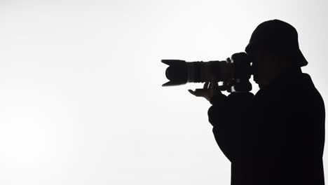 silhouette of a photographer with a long lens taking pictures - concept: focus, subject, wildlife, nature, landscape, professional, craft, hobby
