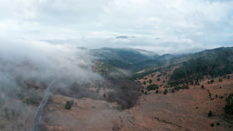 a misty mountain landscape with a winding road, evoking a serene mood, early morning, aerial view
